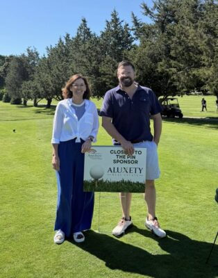 Adeline Matton and Henry Pizzo standing with Closest to the Pin sponsorship sign