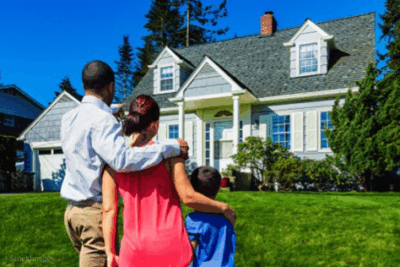 20th Century Family of Three Embracing Facing a House